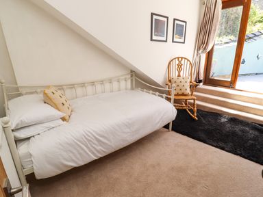 A bedroom with a single bed and a rocking chair near a glass door at Garretts in Kingsand And Cawsand