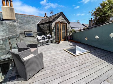 A rooftop terrace with chairs and a glass door opening to the terrace at Garretts in Kingsand And Cawsand