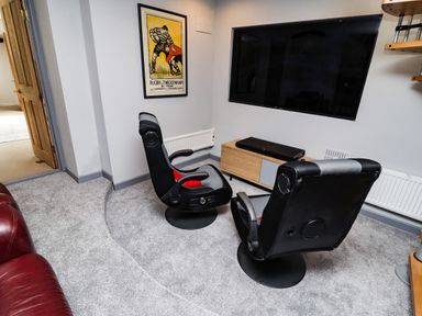 A room with two black gaming chairs facing a wall mounted TV and a wooden TV stand at Garretts in Kingsand And Cawsand