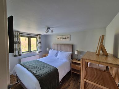 A bedroom with a bed and two bedside tables at Birch Banc Retreats - Bedw Llanidloes