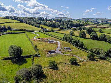 An aerial view of fields and cabins at Birch Banc Retreats - Bedw in Llanidloes