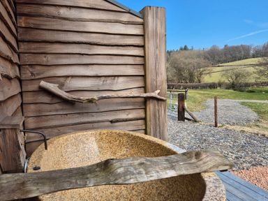 An outdoor shower area with a wooden structure and a bathtub at Birch Banc Retreats - Bedw Llanidloes