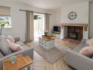 A living room with two grey sofas pink cushions coffee table rug and fireplace at The Miners Cottage in Scremerston near Berwick-Upon-Tweed