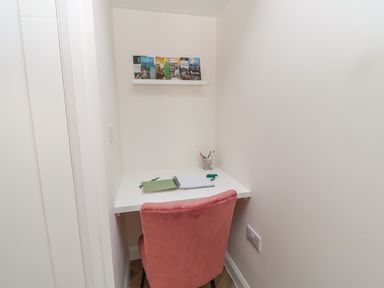A small study area with a white desk and a pink chair at The Miners Cottage in Scremerston near Berwick-Upon-Tweed
