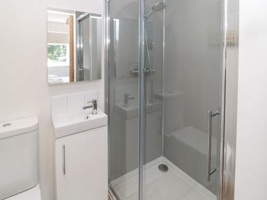 A bathroom with a toilet sink and glass shower enclosure at The Miners Cottage in Scremerston near Berwick-Upon-Tweed