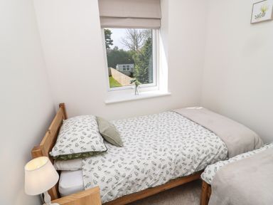 A bedroom with two single beds under a window with a view of a garden at The Miners Cottage in Scremerston near Berwick-Upon-Tweed