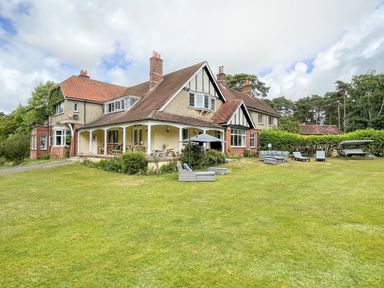 A large house with a covered porch and lawn furniture on the grass at Deer Leap House in Moreton