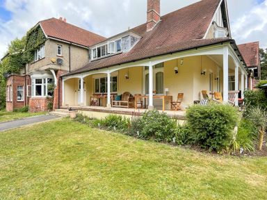 An outdoor patio with chairs tables and plants attached to a house with a sloped roof at Deer Leap House in Moreton