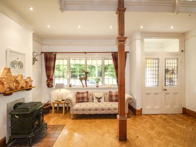 A sitting area with a sofa near windows and a wood-burning stove at Deer Leap House in Moreton