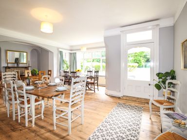 A dining room with wooden tables and white chairs set with dishes and glasses at Deer Leap House in Moreton