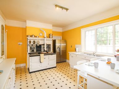 A kitchen with a white stove a stainless steel refrigerator white cabinets and a table set by a window at Deer Leap House in Moreton