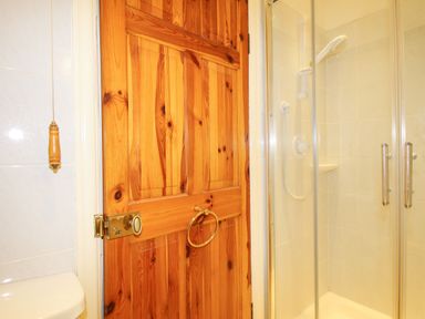 A bathroom door next to a glass shower enclosure with white tiles and a pull cord at Deer Leap House in Moreton