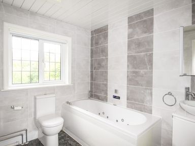 A bathroom with a bathtub toilet sink and a window at Deer Leap House in Moreton