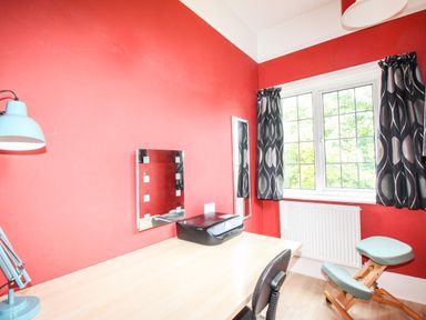 A study room with a desk printer chair blue lamp and window with black curtains at Deer Leap House in Moreton