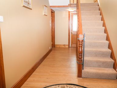 A hallway with beige carpeted stairs and wooden floors at Hazeldene in Sleights