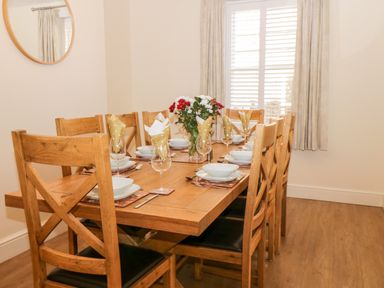 A dining room with a wooden table set with plates glasses napkins and flowers at Hazeldene in Sleights