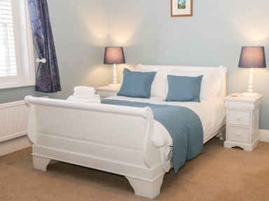 A bedroom with a white bed with blue pillows and blankets and two bedside tables with lamps at Hazeldene in Sleights