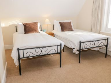 A bedroom with two single beds with white bedding and brown pillows at Hazeldene in Sleights