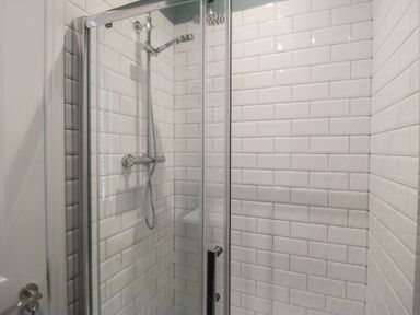 A bathroom shower area with glass doors and white subway tile walls at Hazeldene in Sleights