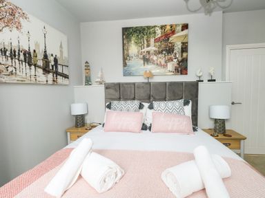 A bedroom with a double bed two bedside tables lamps and wall paintings at The Kings Statue in Weymouth