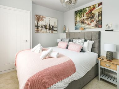 A bedroom with a bed, pillows, bedside table, lamp, artwork on walls at The Kings Statue in Weymouth