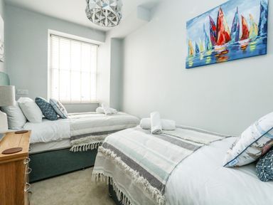 A bedroom with two single beds a window and a painting at The Kings Statue in Weymouth
