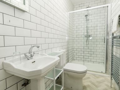 A bathroom with a sink, toilet, glass shower enclosure, and towel rack at The Kings Statue in Weymouth