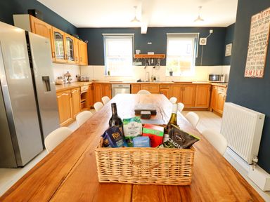 A kitchen with wooden table and various food items at Maples in Hunstanton
