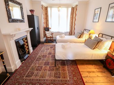 A bedroom with two beds and a rocking chair at Maples in Hunstanton