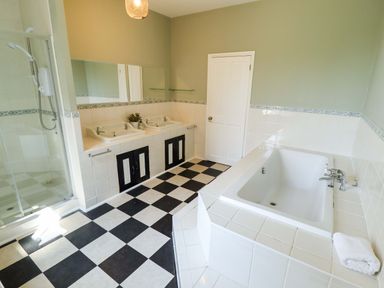 A bathroom with two sinks, a shower, and a bathtub at Maples in Hunstanton