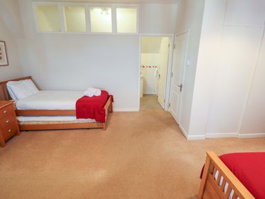 A bedroom with two beds and a bathroom door at Maples in Hunstanton