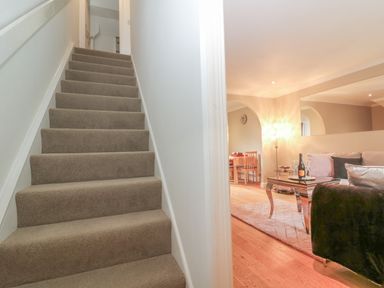 A carpeted staircase next to a living room with a sofa table and dining chairs at The Seventeen in Bourton-On-The-Water