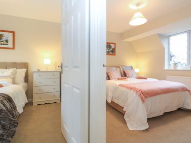 Two bedrooms with beds bedside tables lamps paintings and a window at The Seventeen in Bourton-On-The-Water