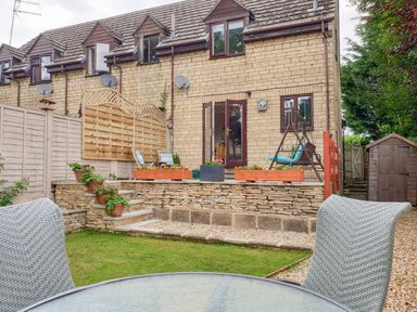 A garden with a stone patio door and outdoor furniture at The Seventeen in Bourton-On-The-Water