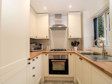 A kitchen with wooden countertops a gas stove an oven a microwave a sink and cabinets at The Seventeen in Bourton-On-The-Water