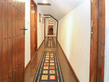 A hallway with wooden doors rugs on the floor and white walls at The Old Barn in Walcott