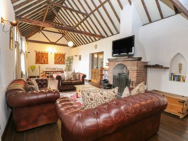 A living room with leather sofas a brick fireplace and a dining table at The Old Barn in Walcott
