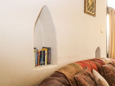 A living room wall with a built-in niche holding books above a sofa with cushions at The Old Barn in Walcott