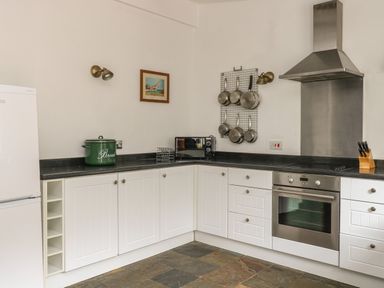 A kitchen with white cabinets pots hanging on the wall and a stainless steel oven at The Old Barn in Walcott