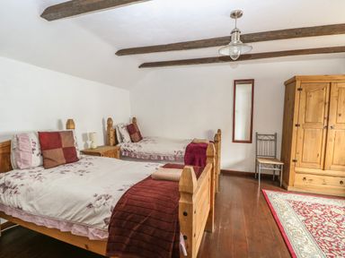 A bedroom with two single beds a wooden wardrobe a chair and a mirror at The Old Barn in Walcott