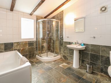 A bathroom with a bathtub a corner shower a pedestal sink and a toilet at The Old Barn in Walcott