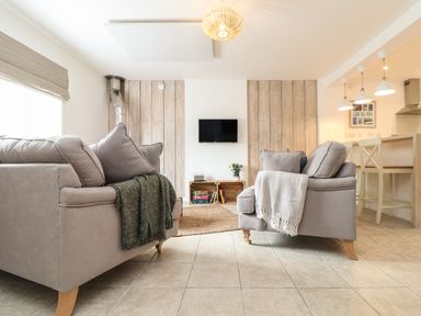 A living room with two gray sofas and a wall-mounted TV at The Old Post Office in Porthleven