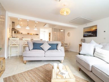 A living room with sofas and a wooden coffee table with mugs and a book at The Old Post Office in Porthleven