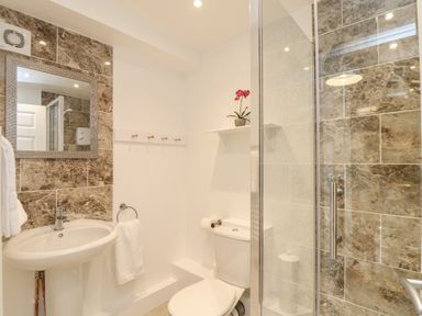 A bathroom with a sink toilet and glass shower at The Old Post Office in Porthleven