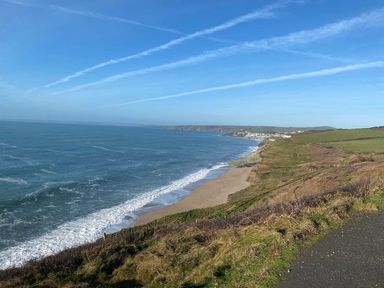 A coastal landscape with cliffs grassy fields and a beach at The Old Post Office in Porthleven