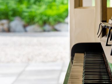 A close-up of a piano keyboard with an outdoor garden visible through an open door at Silverholme in Graythwaite near Hawkshead