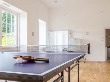 A table tennis table with a paddle and ball in a room with wooden floor and white walls at Silverholme Graythwaite near Hawkshead