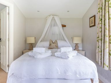 A bedroom with a double bed covered with white bedding and towels with two bedside tables and lamps at Silverholme in Graythwaite near Hawkshead