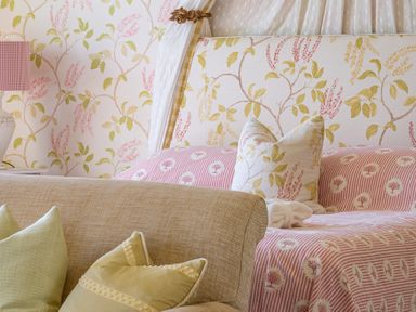 A bedroom with floral patterned bed and headboard with pillows and a beige sofa with green pillows at Silverholme Graythwaite near Hawkshead
