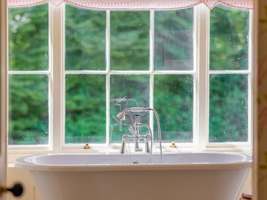 A bathtub with a faucet in front of a window at Silverholme in Graythwaite near Hawkshead